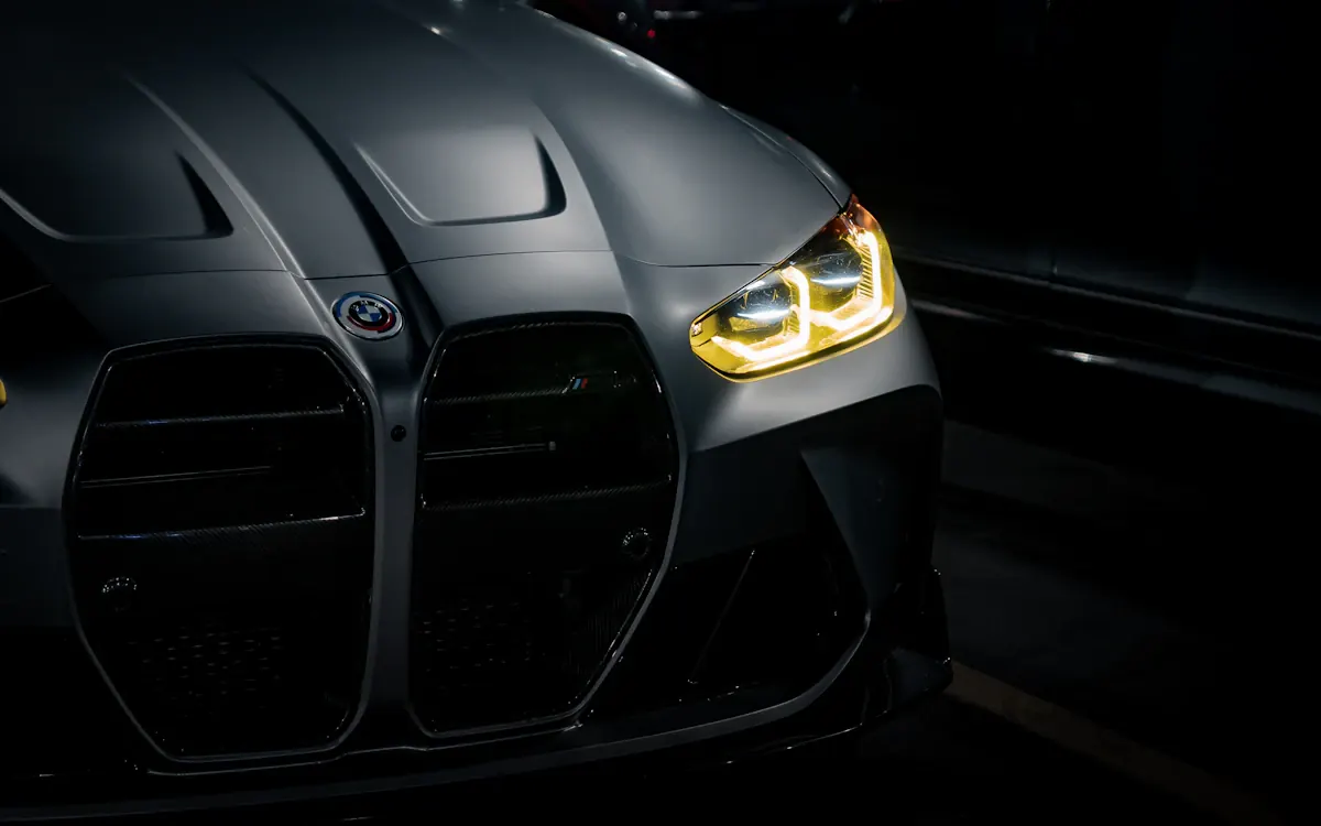 Illuminated BMW headlights in a dark automotive portrait