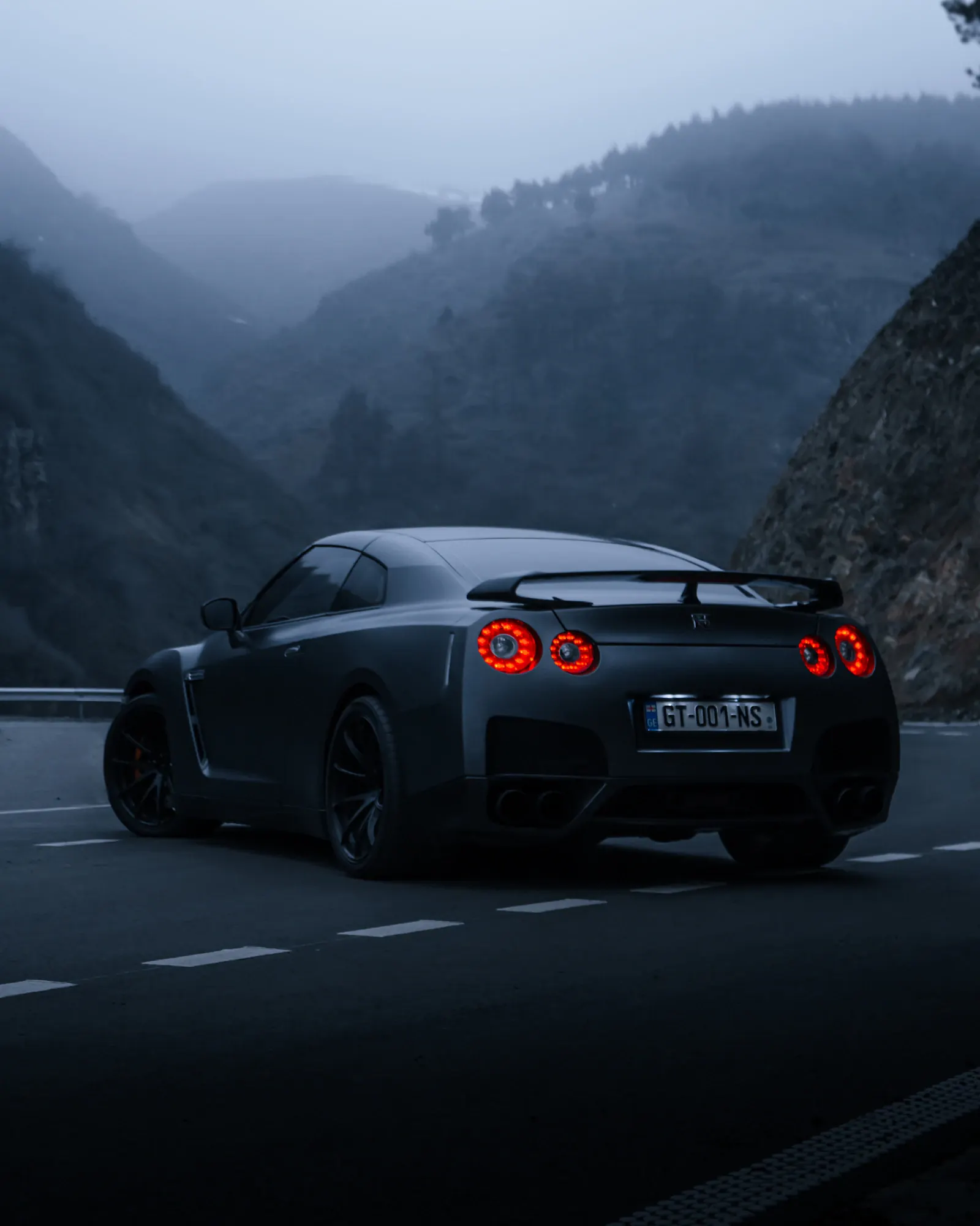 Rear view of a dark Nissan GT-R on a mountain road